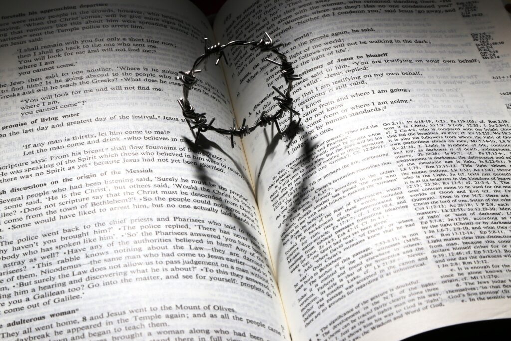 crown of thorns makes aheart shape shadow on an open Bible